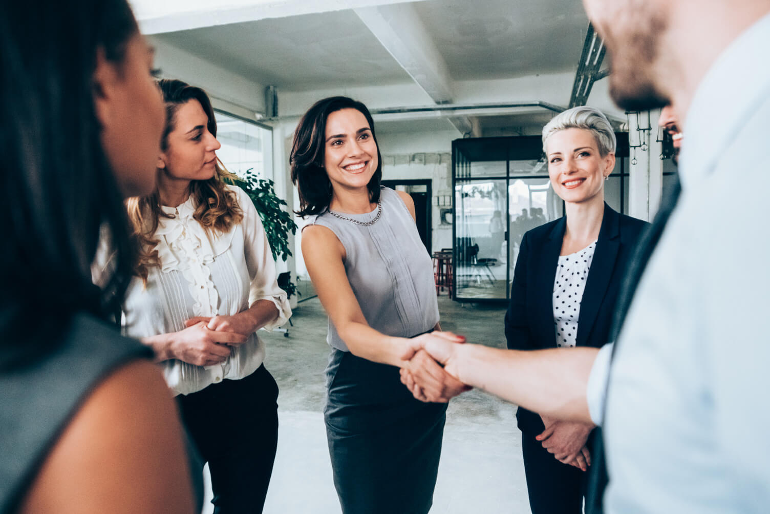 A manager shaking hands with her new hire afte being introduced to him by her team.