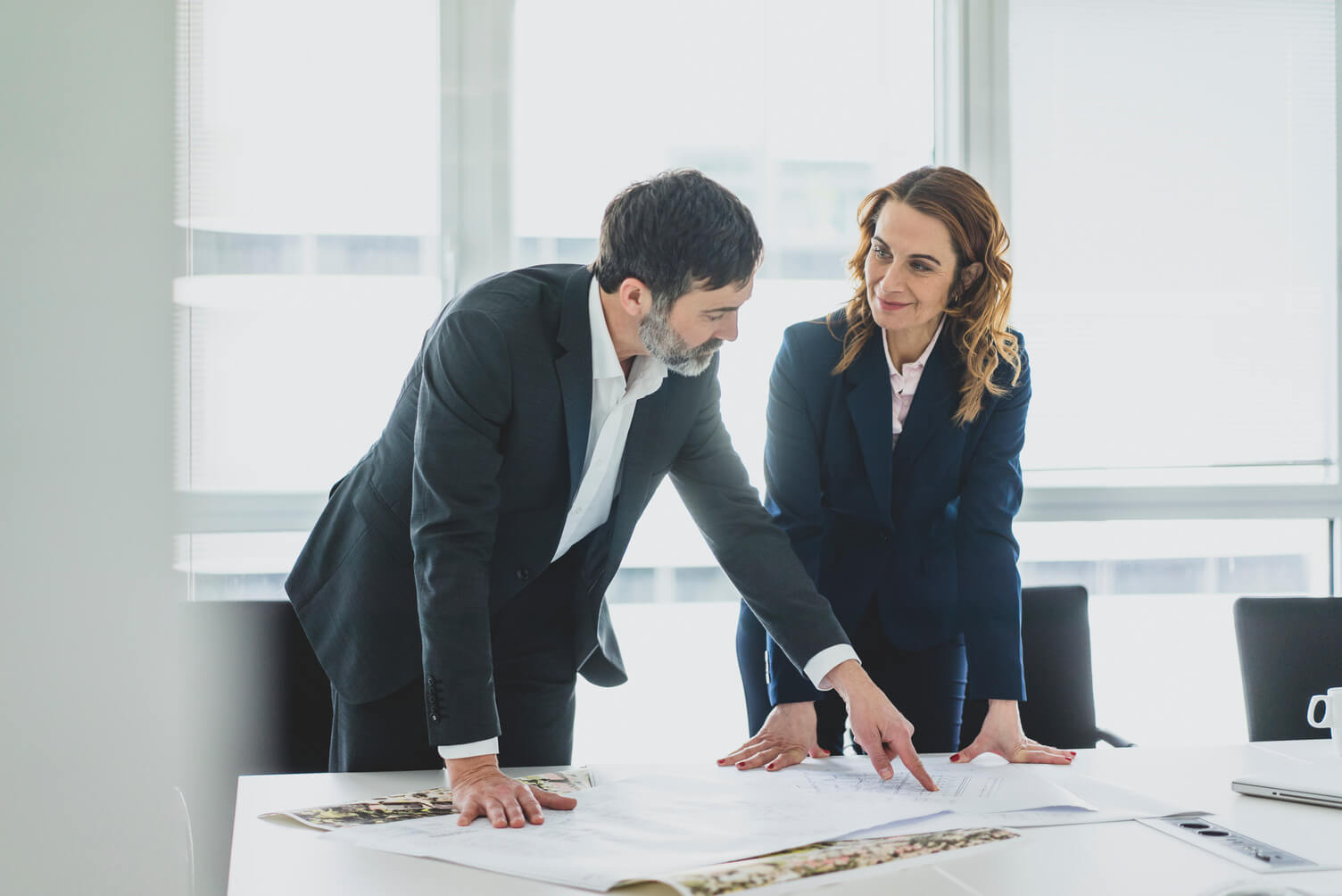 Businesswoman and businessman working on plan on desk in office - stock photo