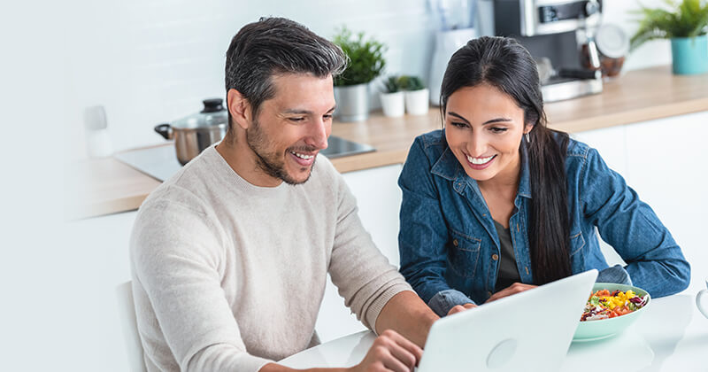 Couple using laptop in kitchen