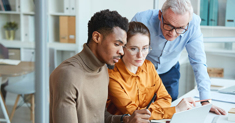 Three business people meeting around laptop