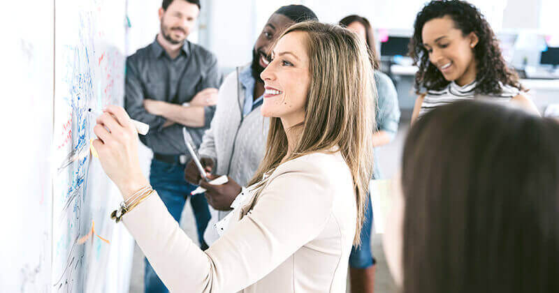 Colleagues looking at businesswoman writing notes