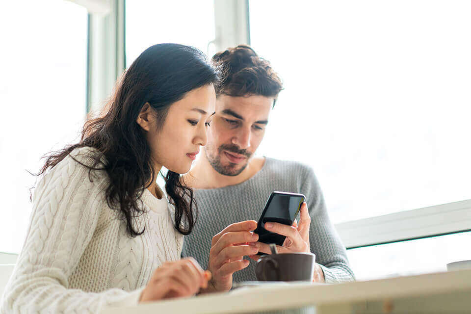 Couple using smart phone dining room