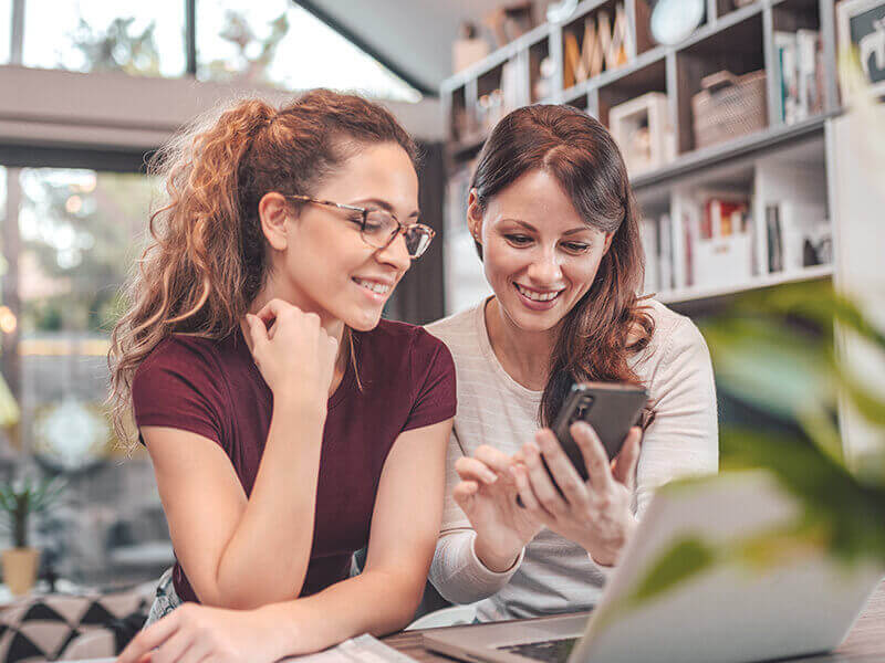 Two smiling woman looking at smart phone