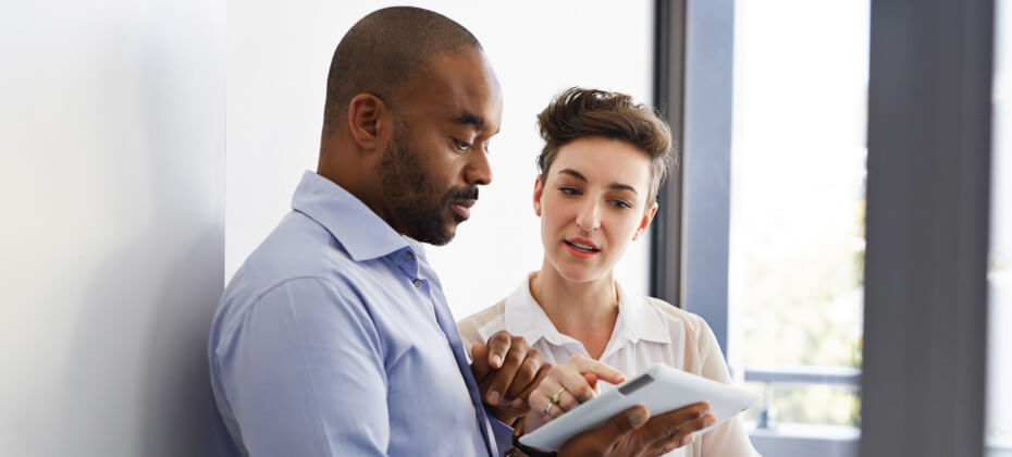 business man and woman speaking and pointing to tablet